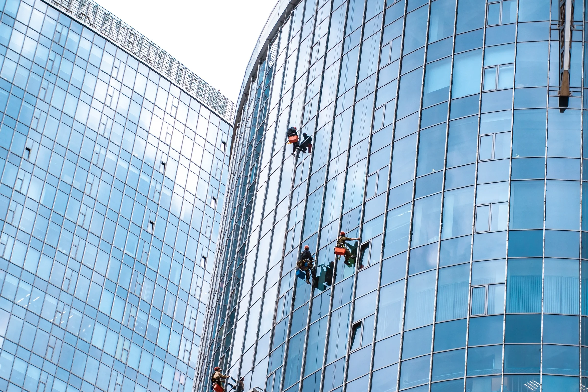 Vinduesvask med rope access pa stor skyskraber vinduesfacade udefra